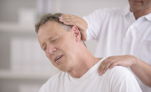 A nyak osteochondrosisában szenvedő férfi egy kézi masszőrrel folytatott konzultáción